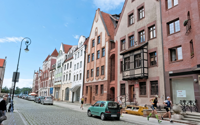 15 - A cobblestone street with runners and historic-style buildings in the Old Town of Elbląg, Poland